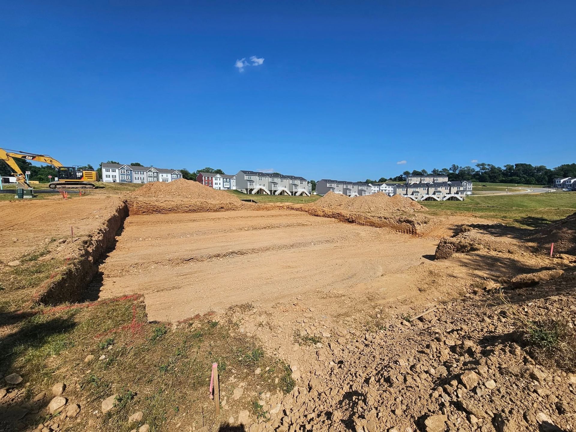 A construction site with a lot of dirt and a house in the background.