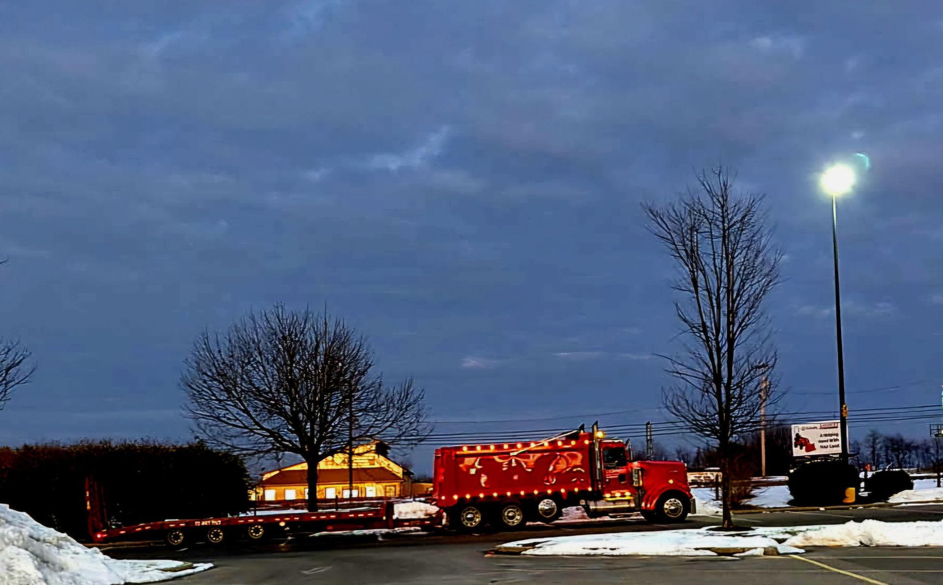 A red truck is parked in a snowy parking lot.
