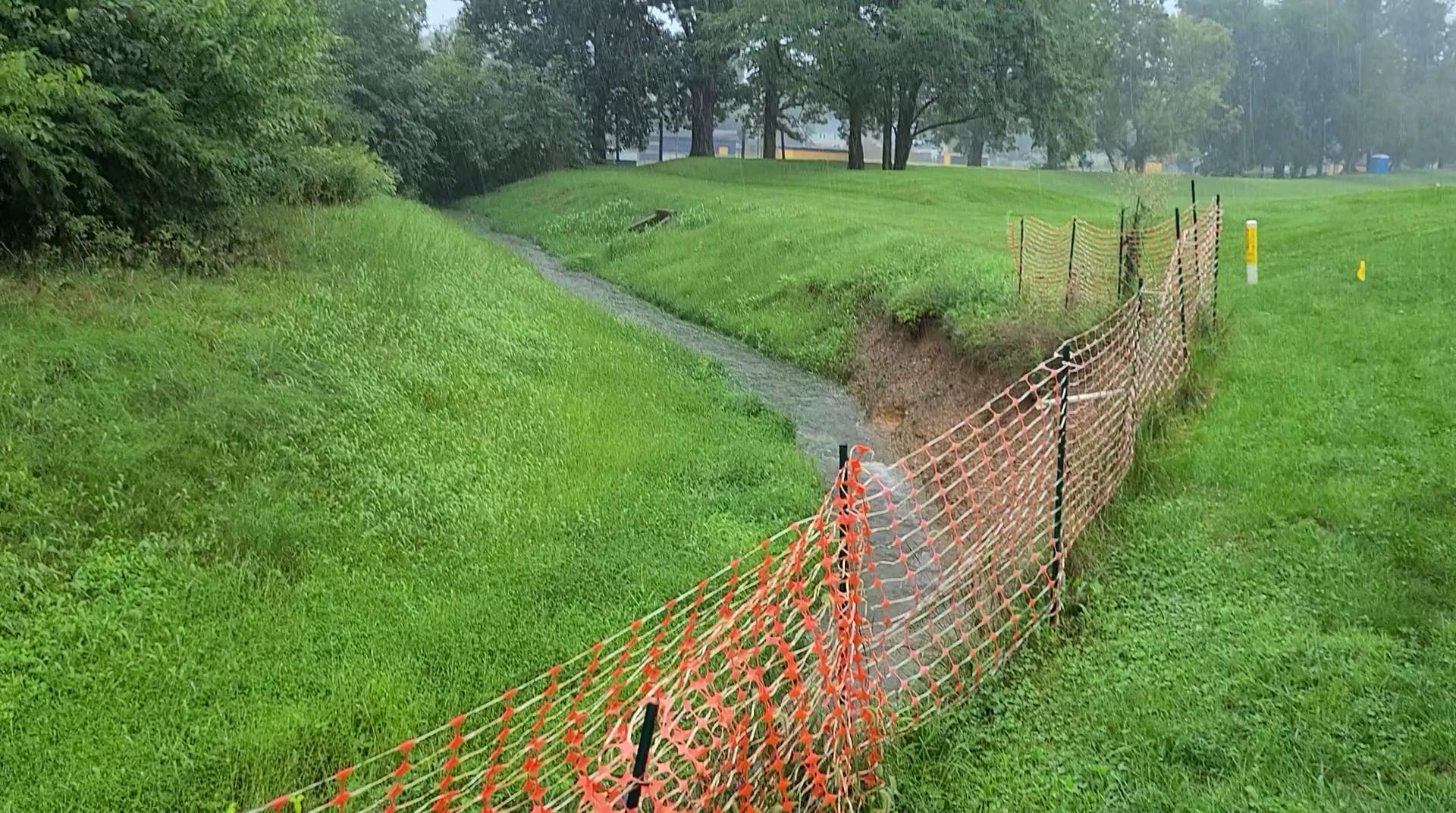 A stream is surrounded by a fence in a park.