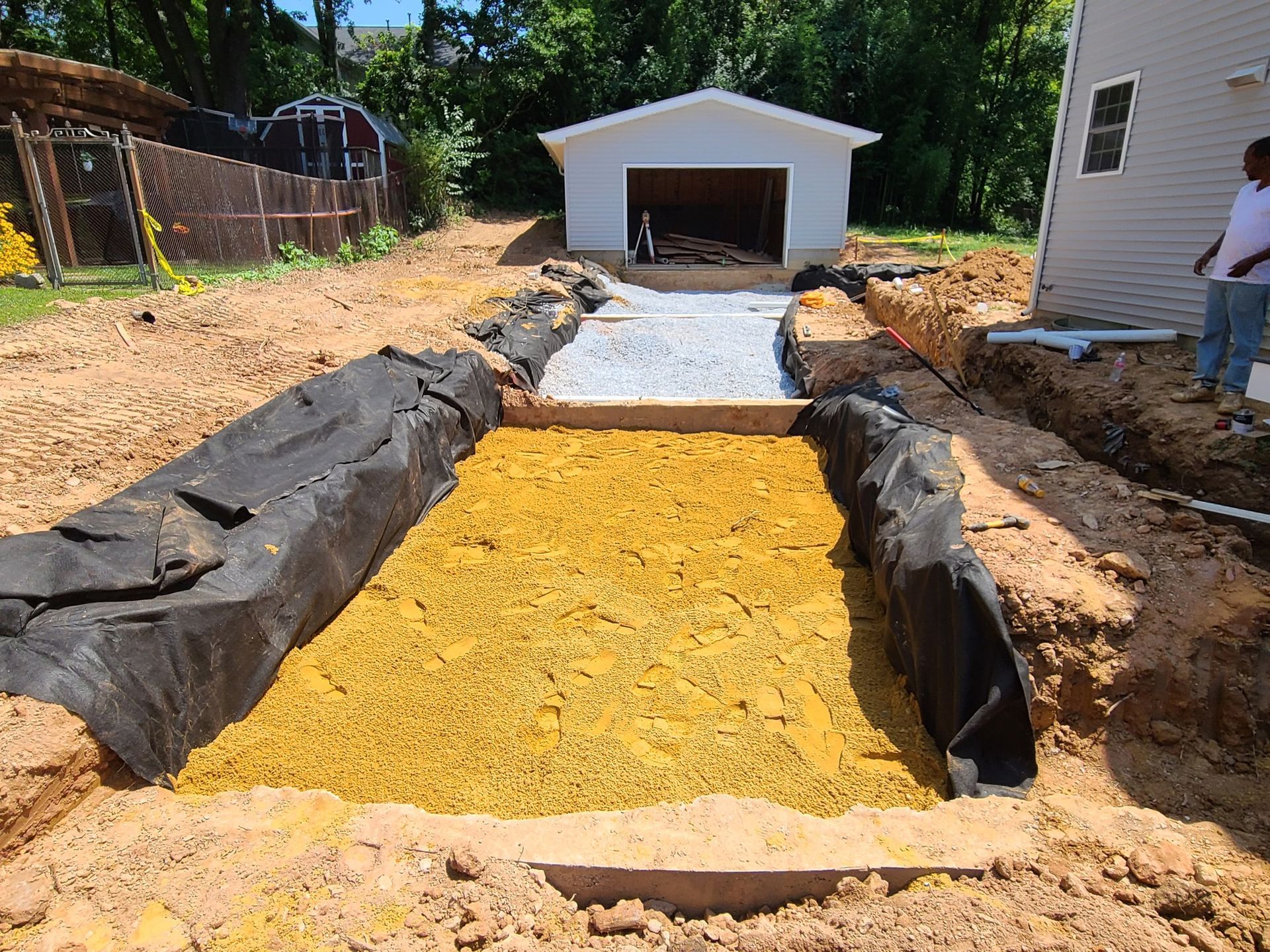 A man is standing next to a pile of dirt in front of a garage.