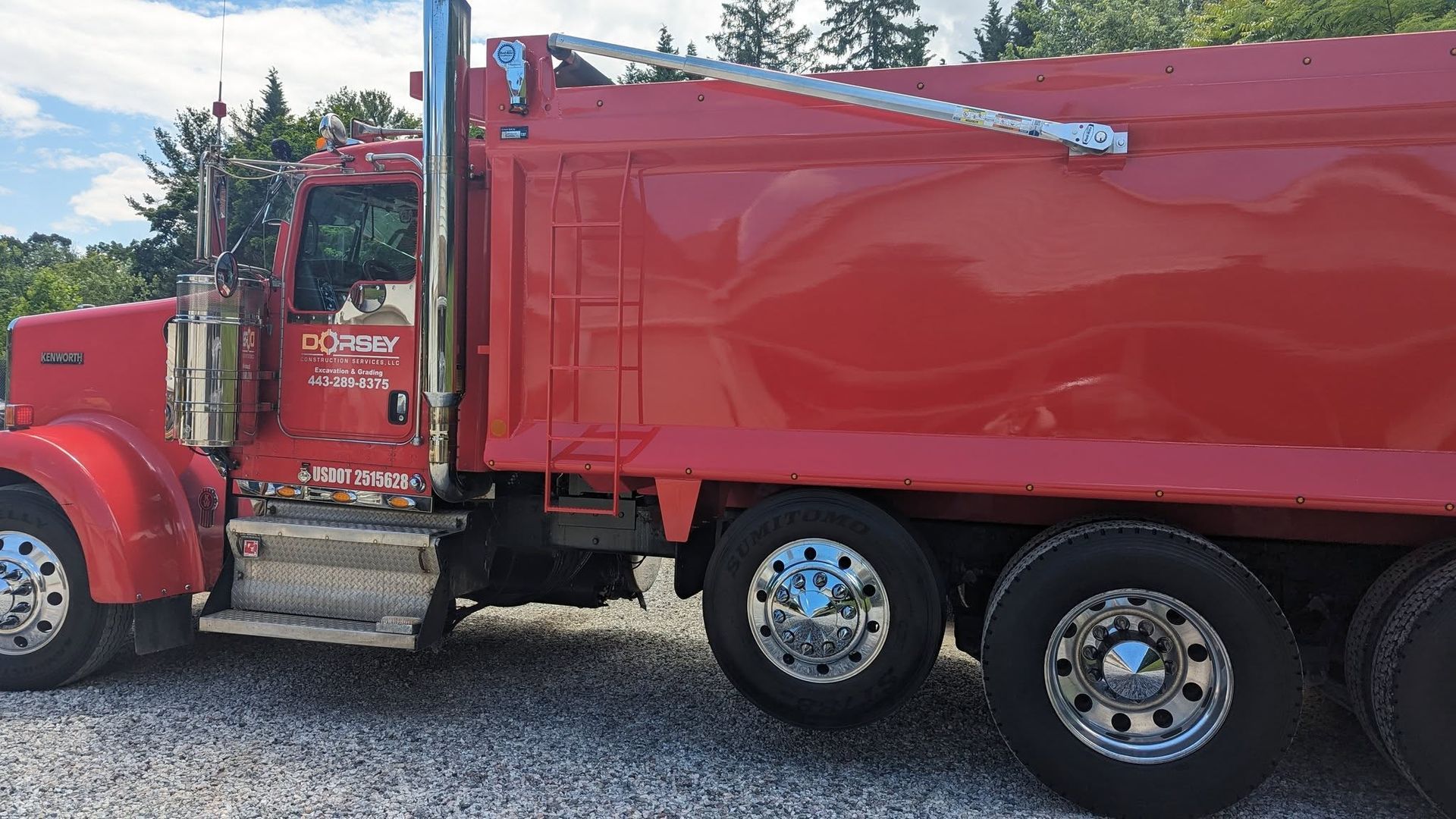 A red dump truck is parked in a gravel lot.
