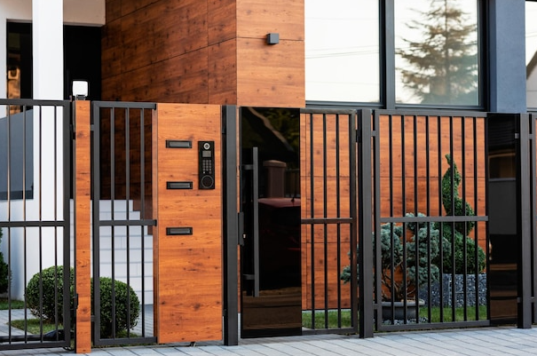 Modern house entrance with wood panels, metal gate, mailbox, and door.