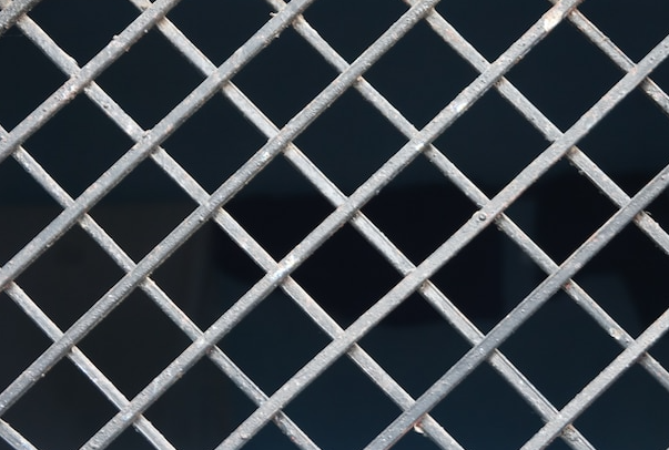 Diamond pattern metal grate over a dark background.