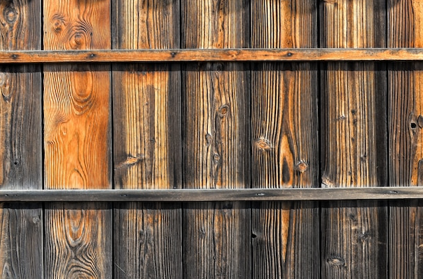 Wooden wall with varying colors of brown and black planks, horizontal dark bands.