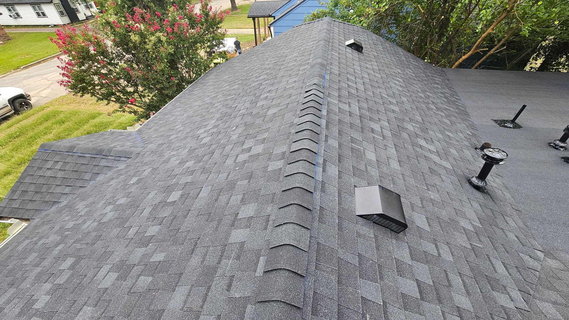 Gray asphalt shingle roof with ridge vent and exhaust vents, viewed from above.