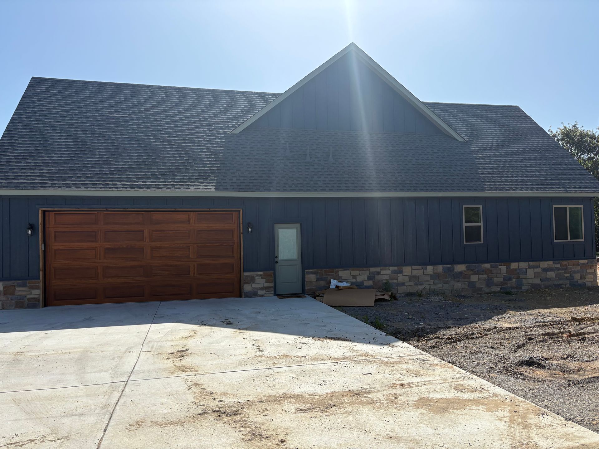 Blue house with brown garage door and a concrete driveway, under a clear sky.