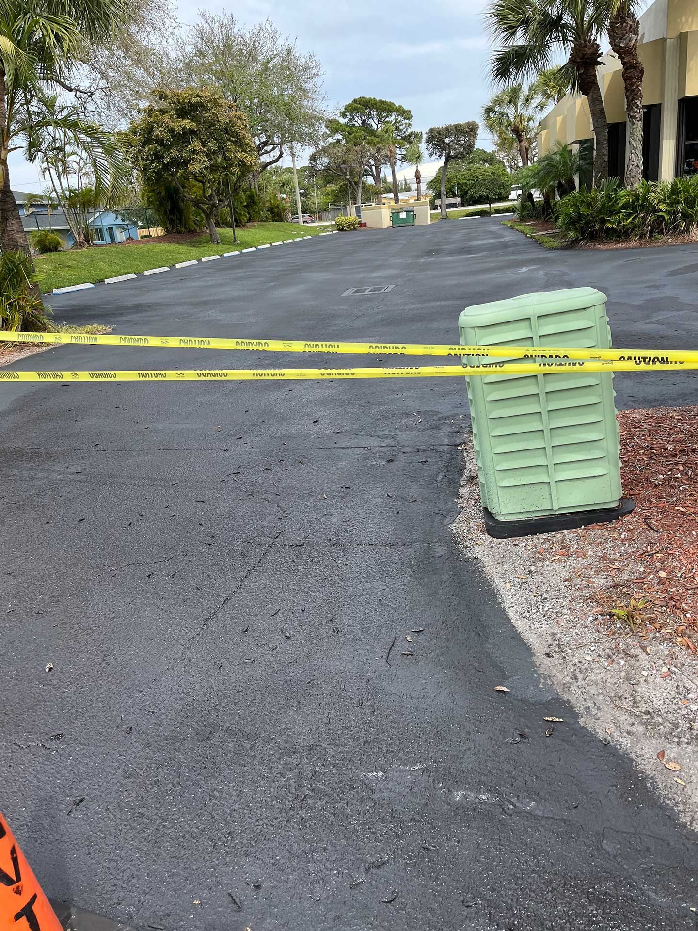 a green box on the side of a newly paved driveway