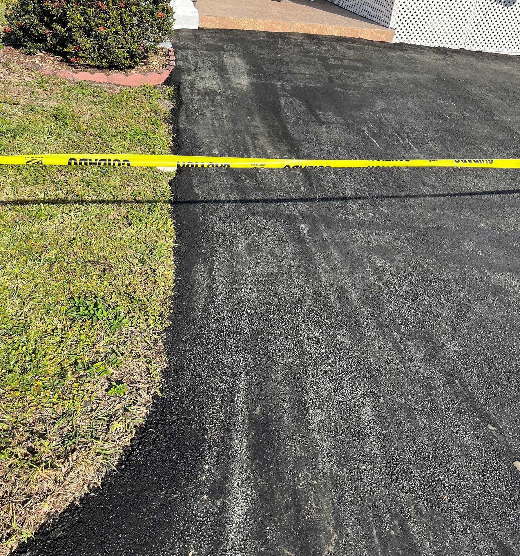a black asphalt driveway with a yellow caution tape