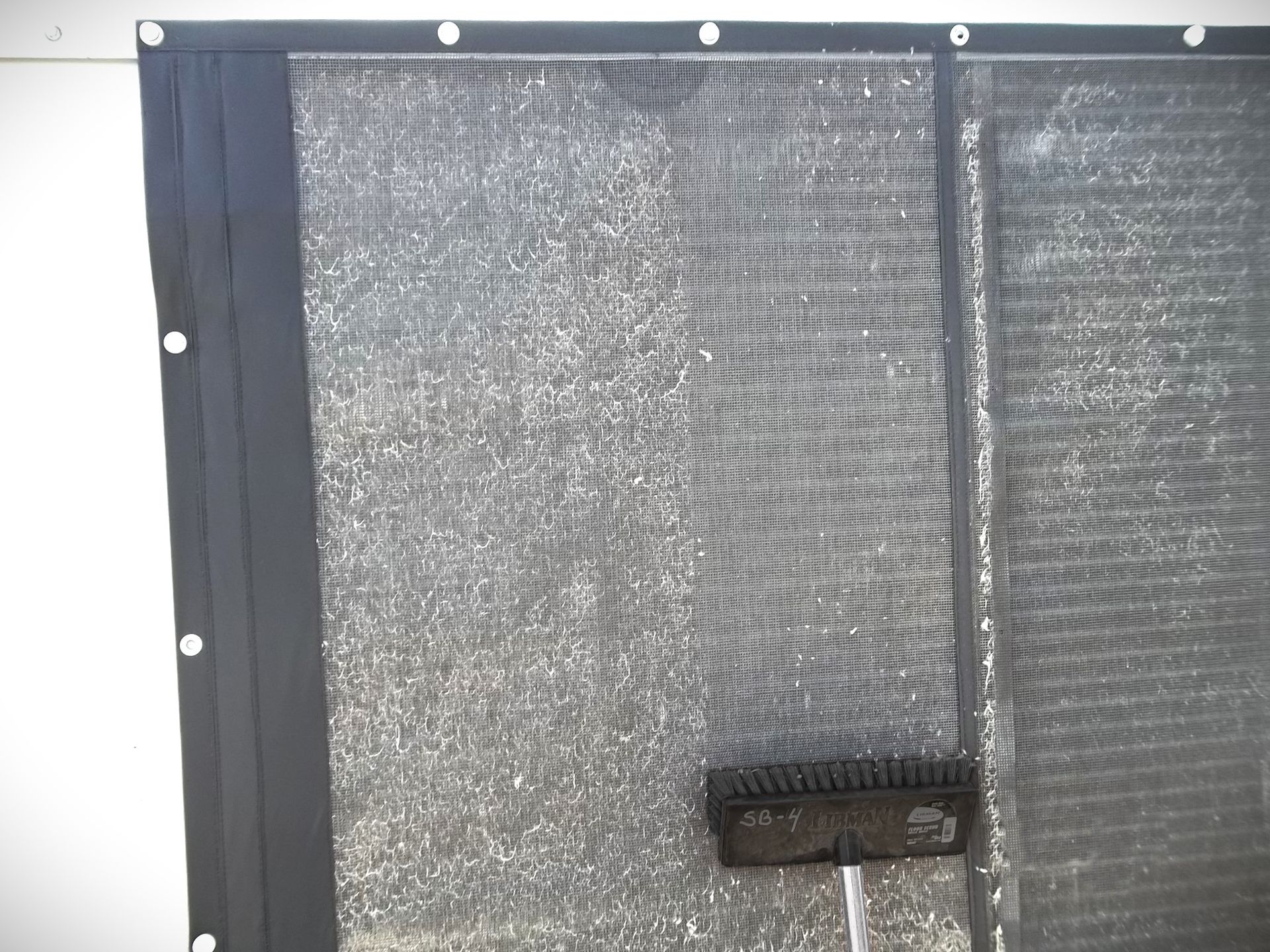 A close up of a screen with a cleaning brush removing debris.