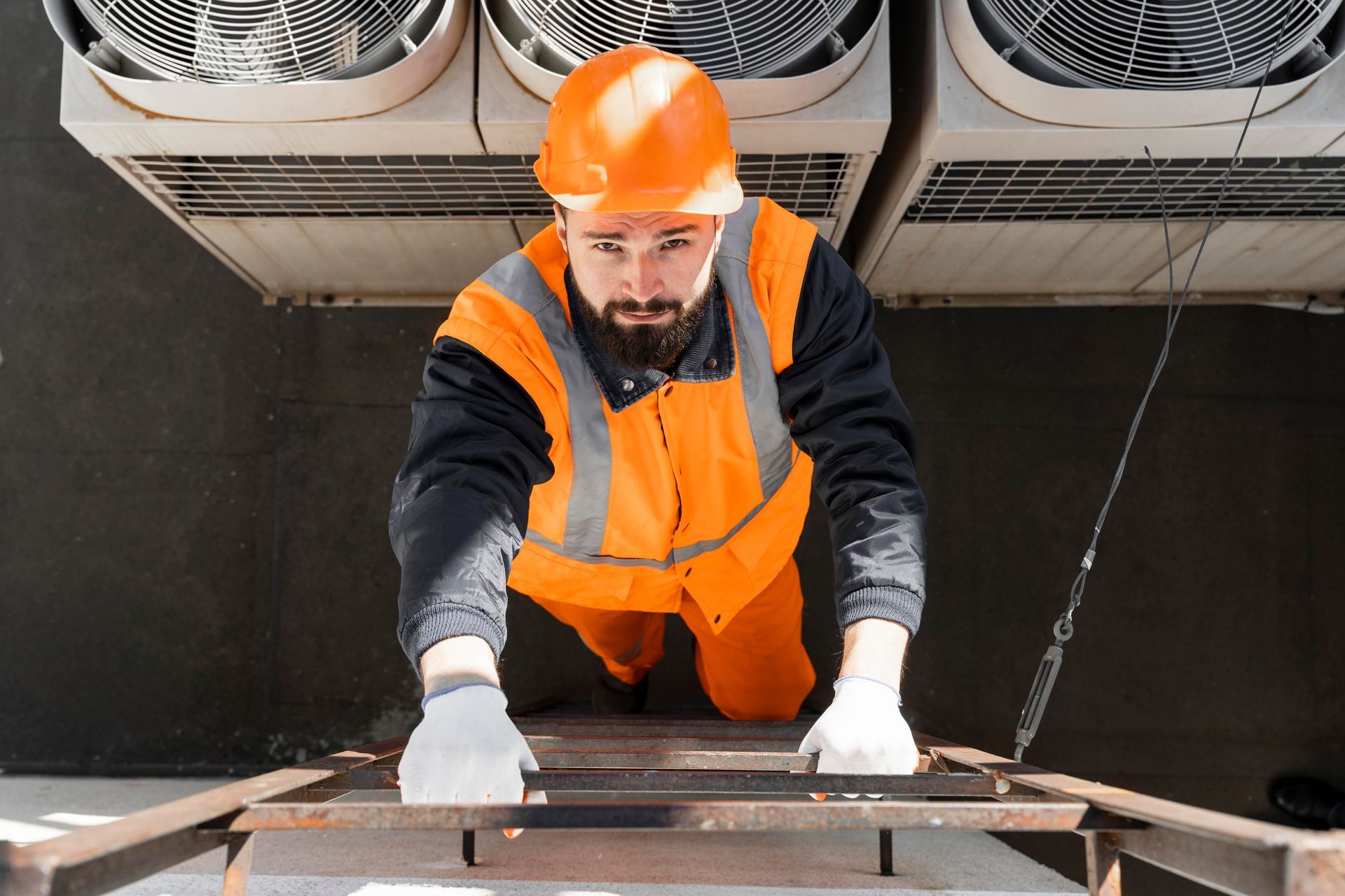 A man in a hard hat is climbing up a ladder.