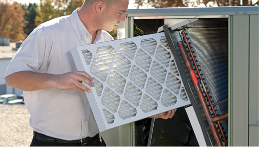 A man is installing a new filter in an air conditioning unit.