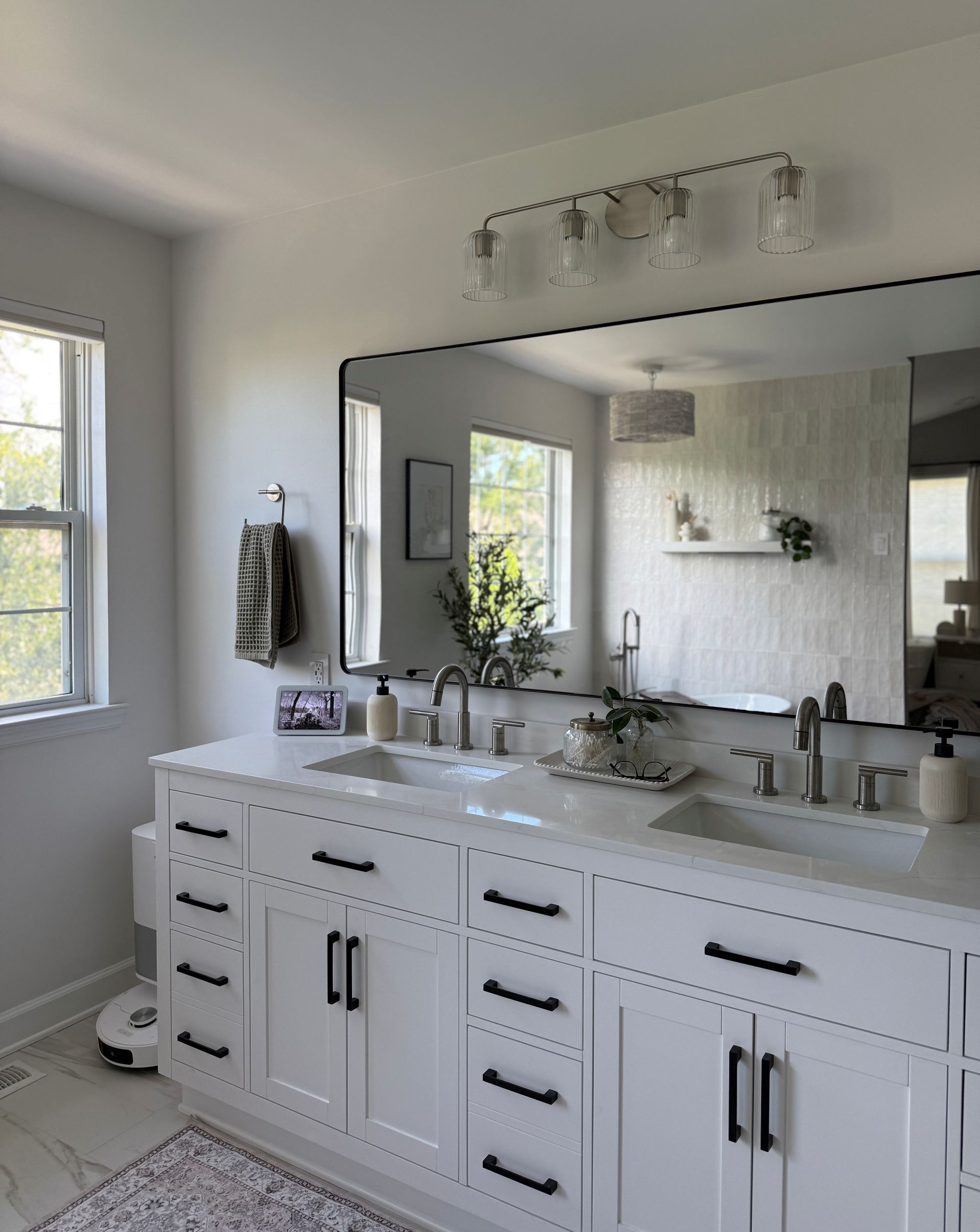 Bright modern bathroom with white vanity, large mirror, double sinks, and chrome fixtures