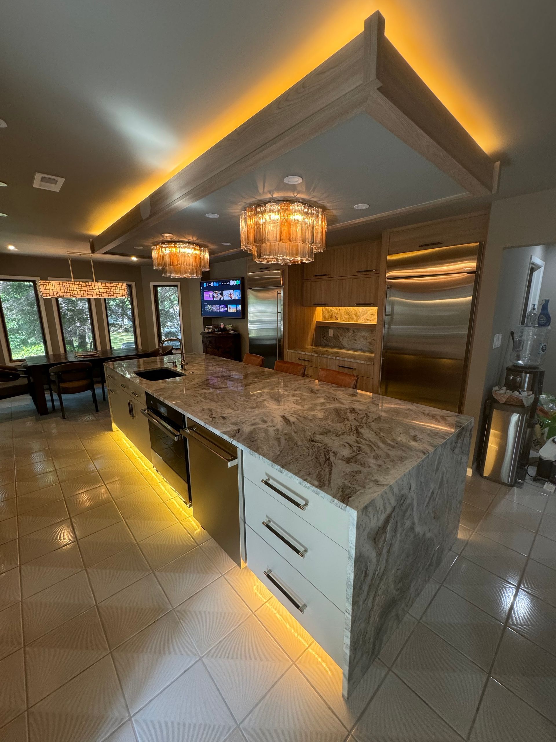Luxury kitchen with granite island, pendant lights, stainless appliances, and warm ceiling lighting