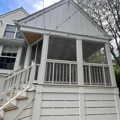 A white house with a screened in porch and stairs.