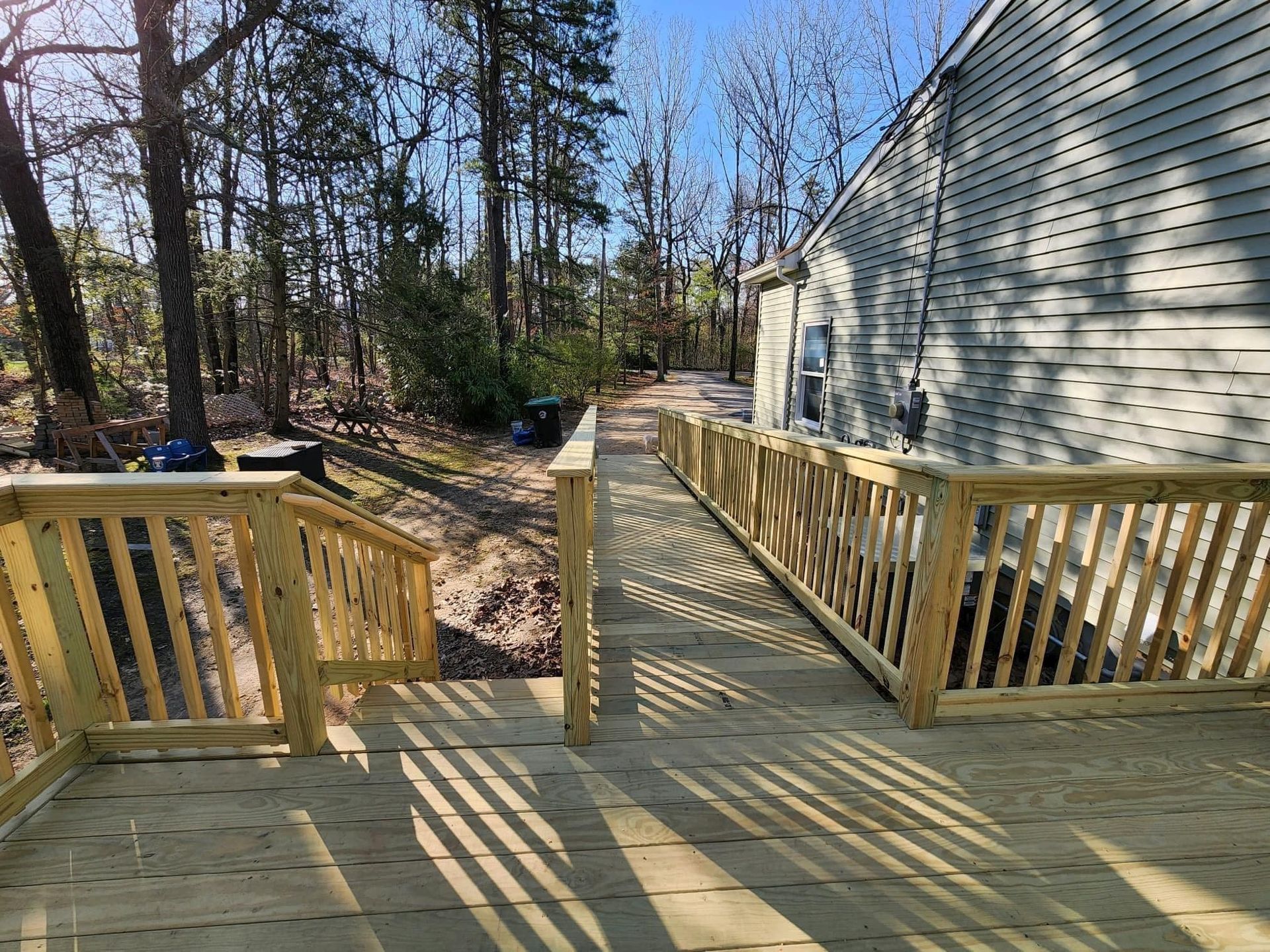 A wooden deck with stairs leading to a house in the woods.
