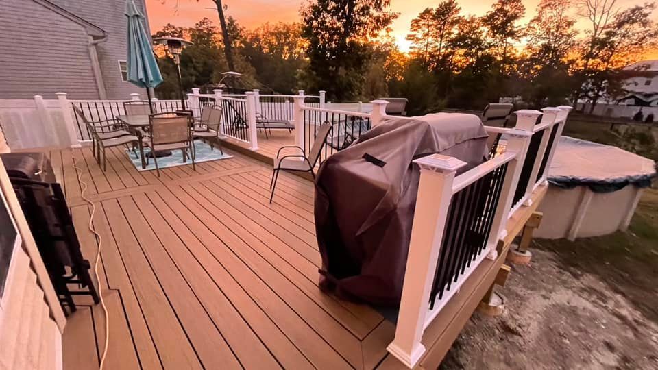A large wooden deck with a couch and chairs on it.