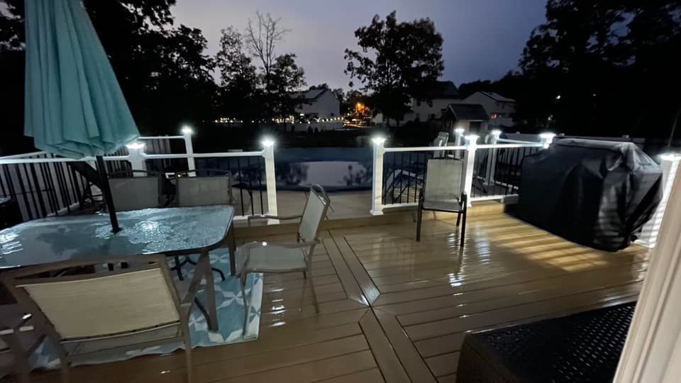 A deck with a table and chairs and an umbrella at night.