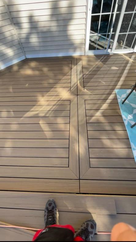 A person is standing on a wooden deck with a skateboard.