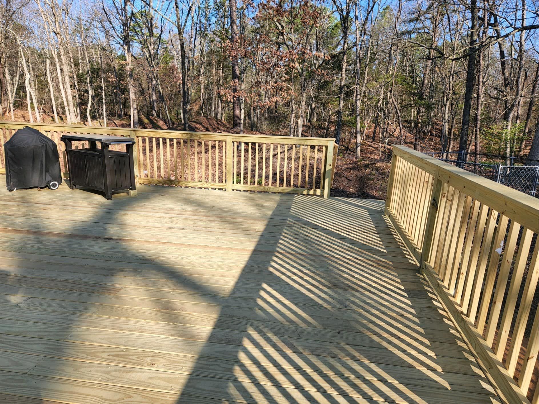 A wooden deck with a wooden railing in the woods.