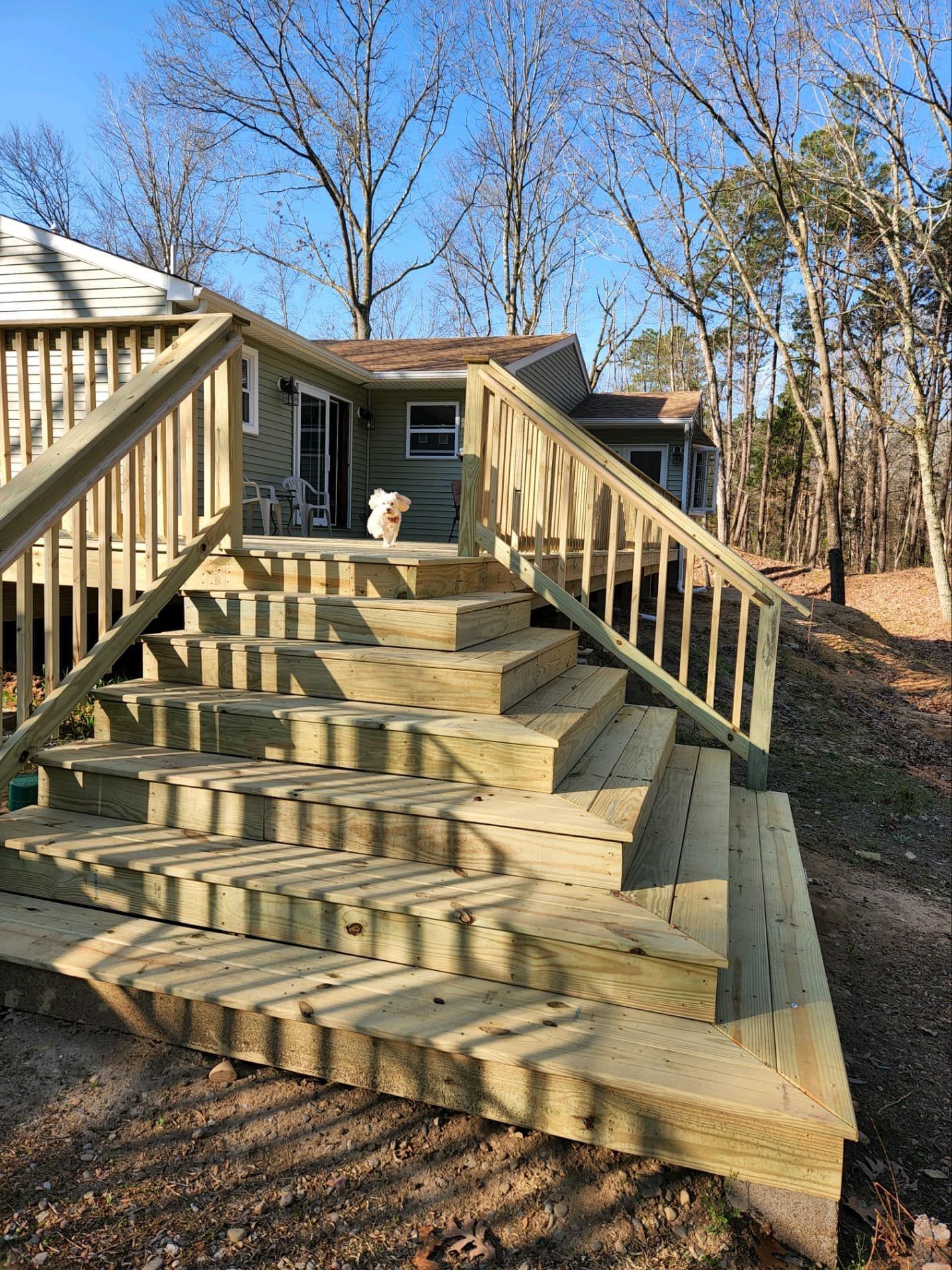 A wooden deck with stairs leading up to it and a house in the background.