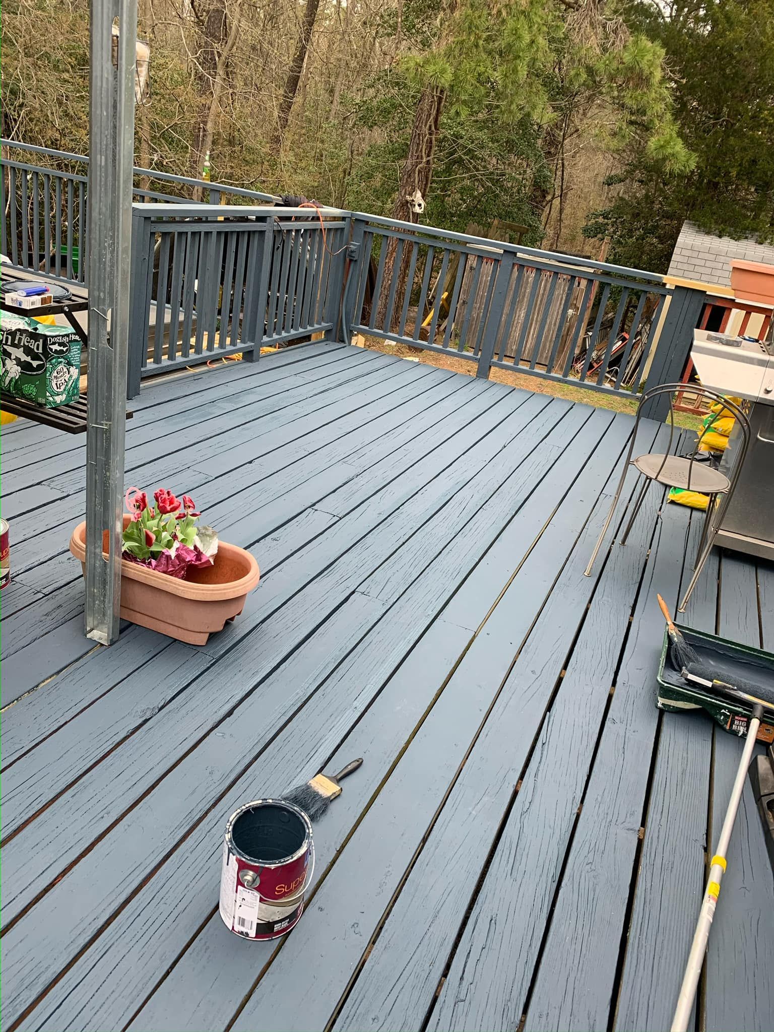 A can of paint is sitting on a wooden deck.