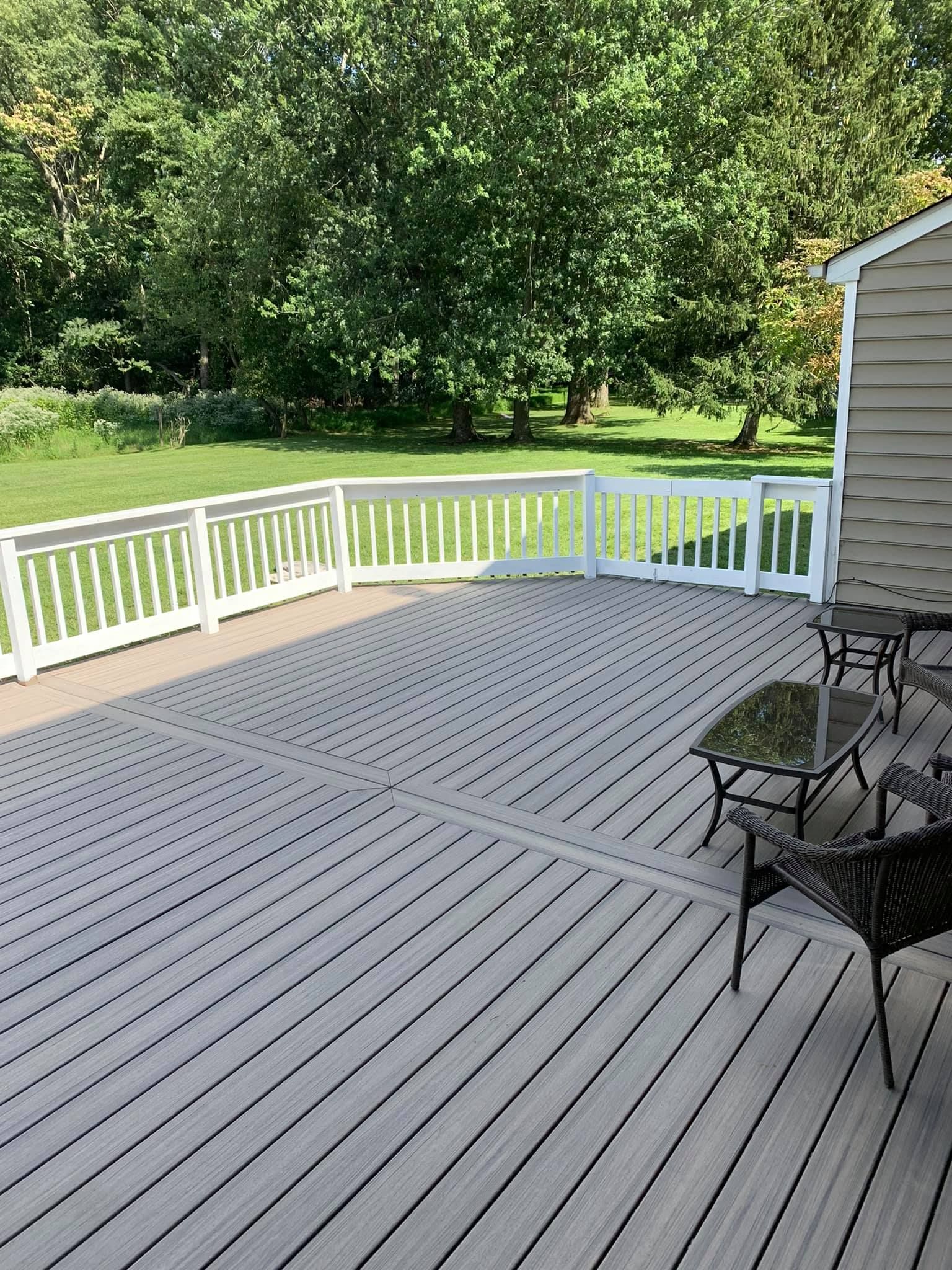 There is a large deck with a white railing and chairs on it.
