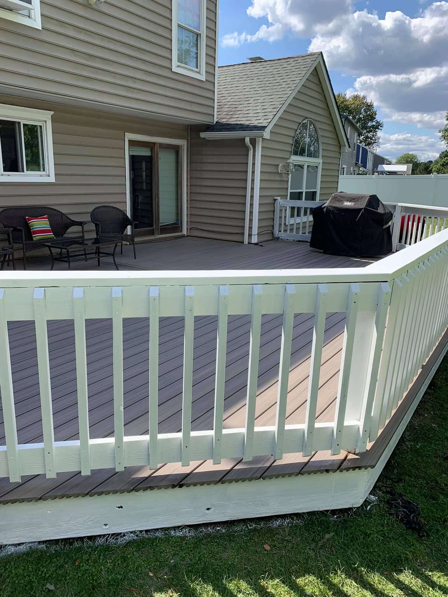 A large deck with a white railing in front of a house.