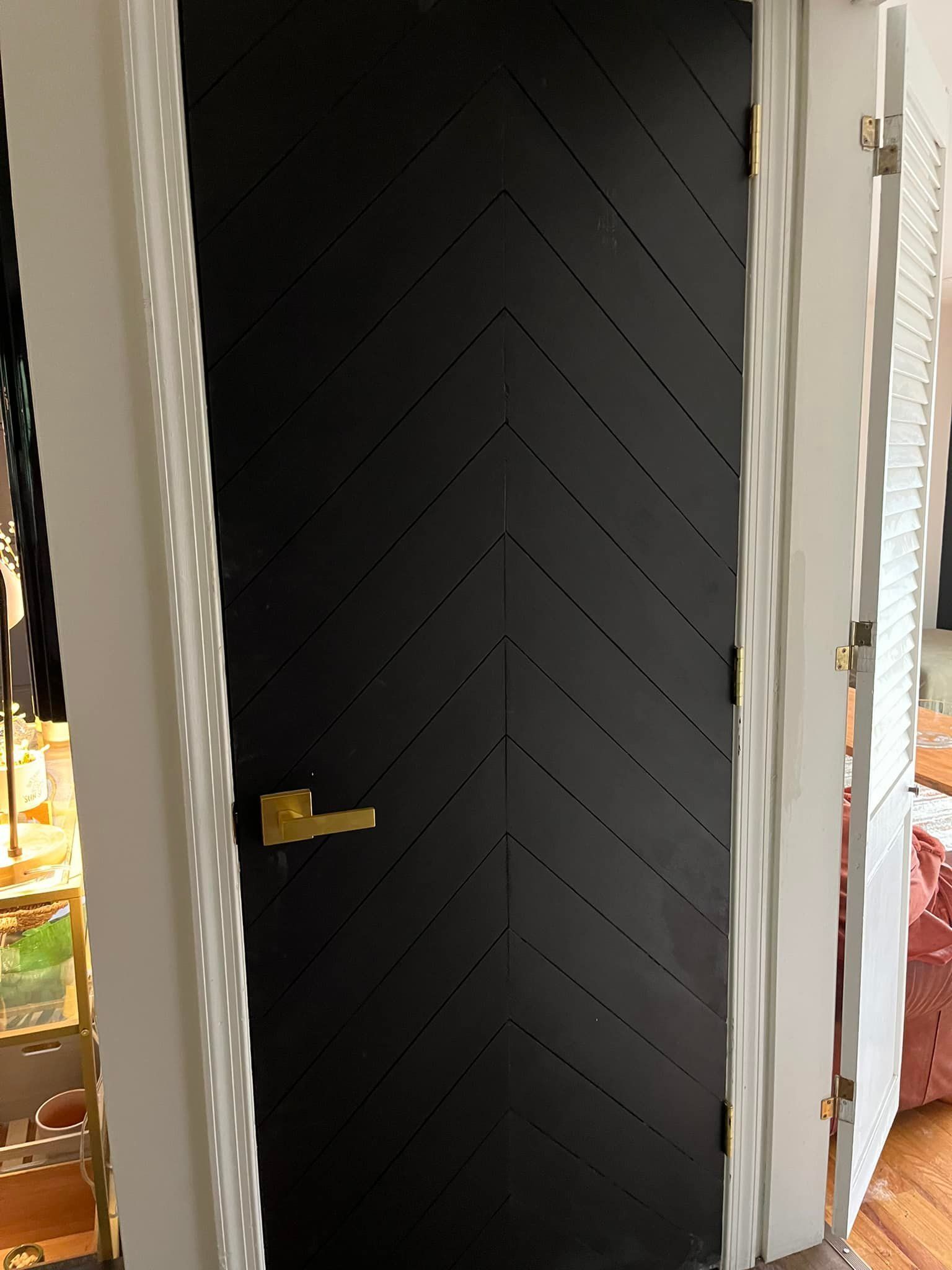 A black door with a gold handle is in a hallway.