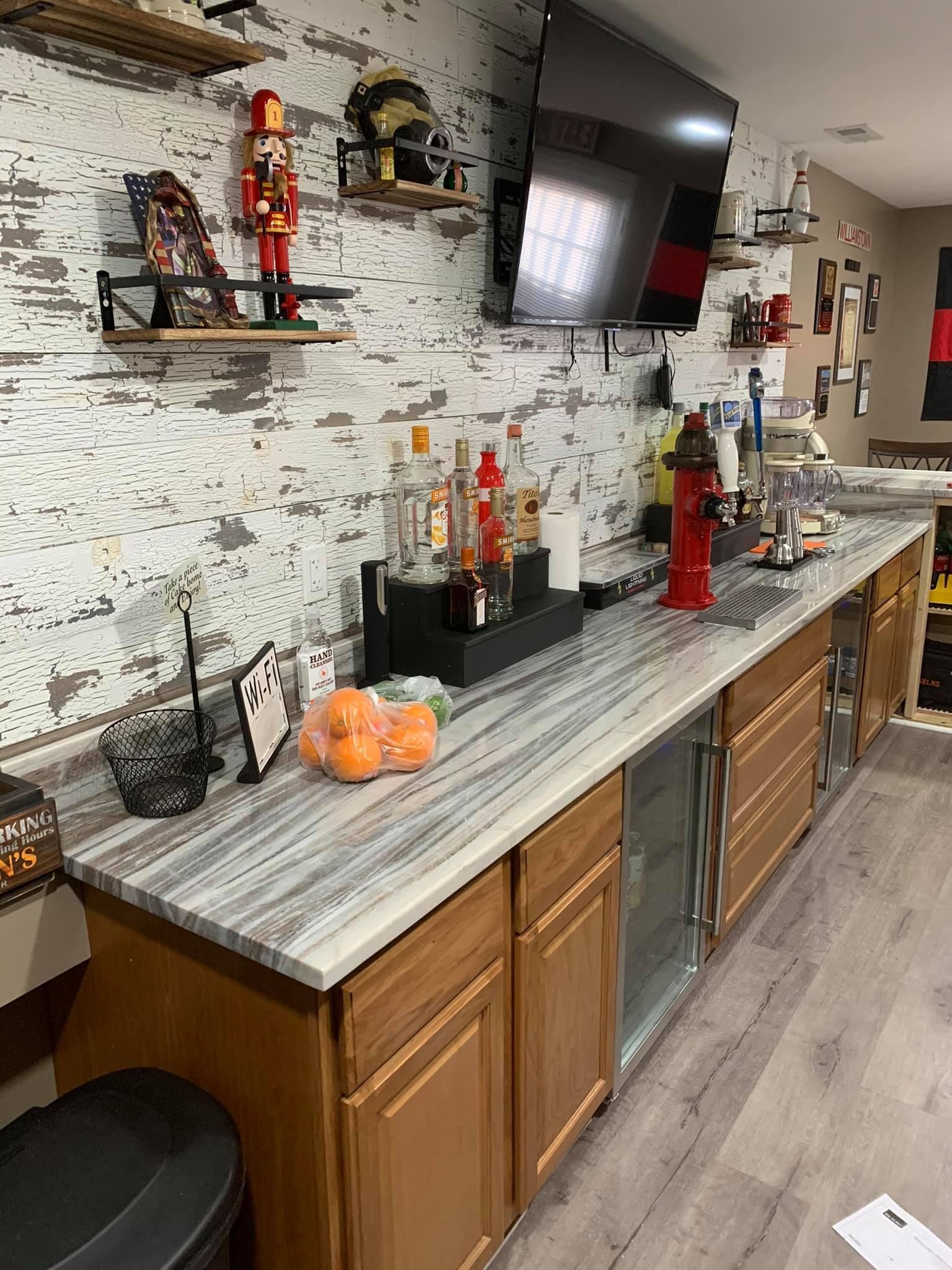 A kitchen with a long counter and a tv on the wall.