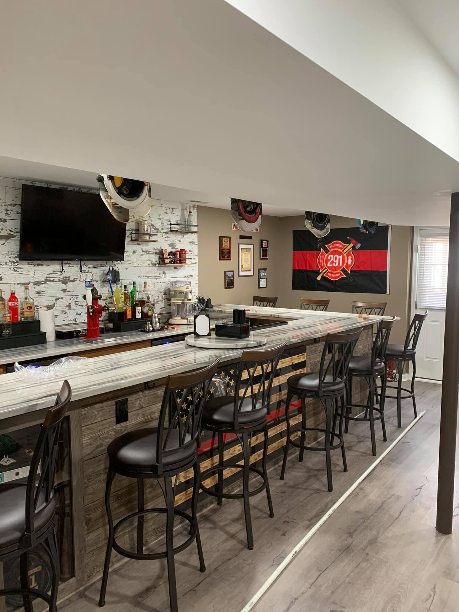 A bar with a long counter and stools in a basement.