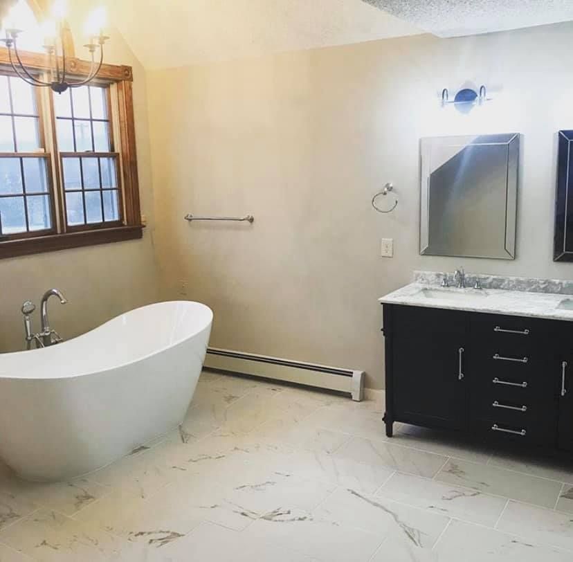 A bathroom with a tub a sink and a mirror