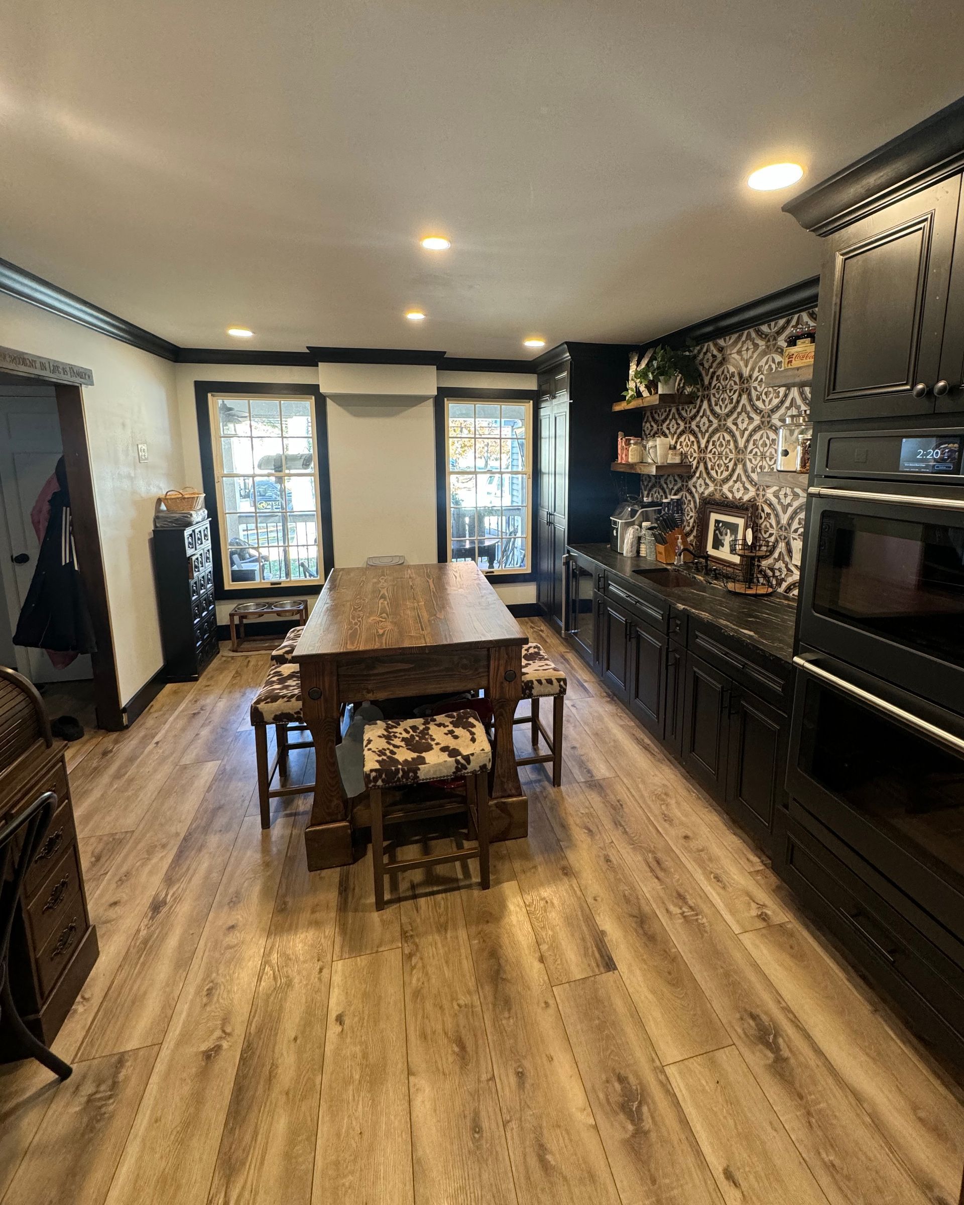 Dining room with a dark, rustic table and chairs, dark cabinets, and wood-look floors.
