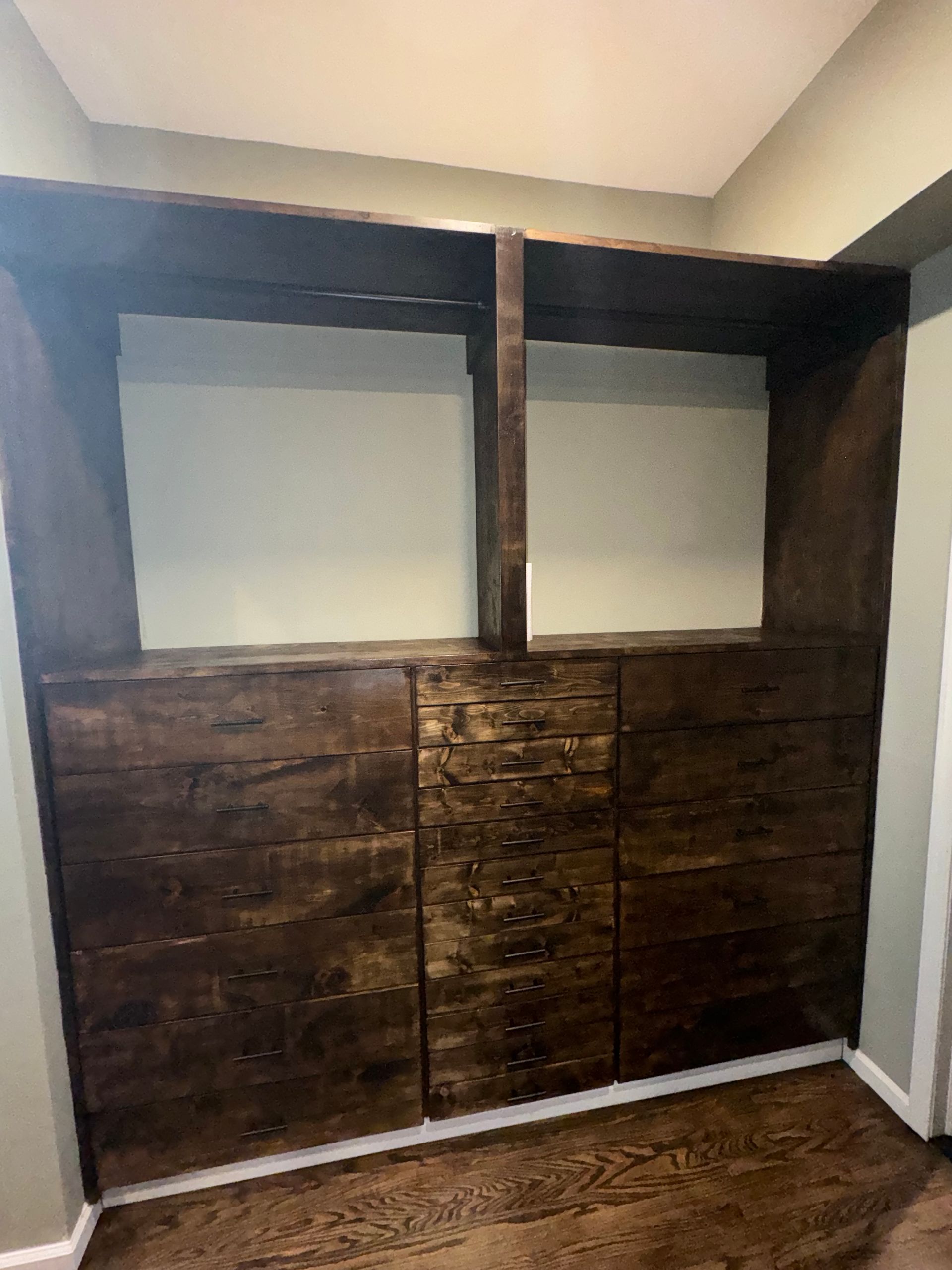 Wooden built-in shelving unit with dark finish and three lower drawers.