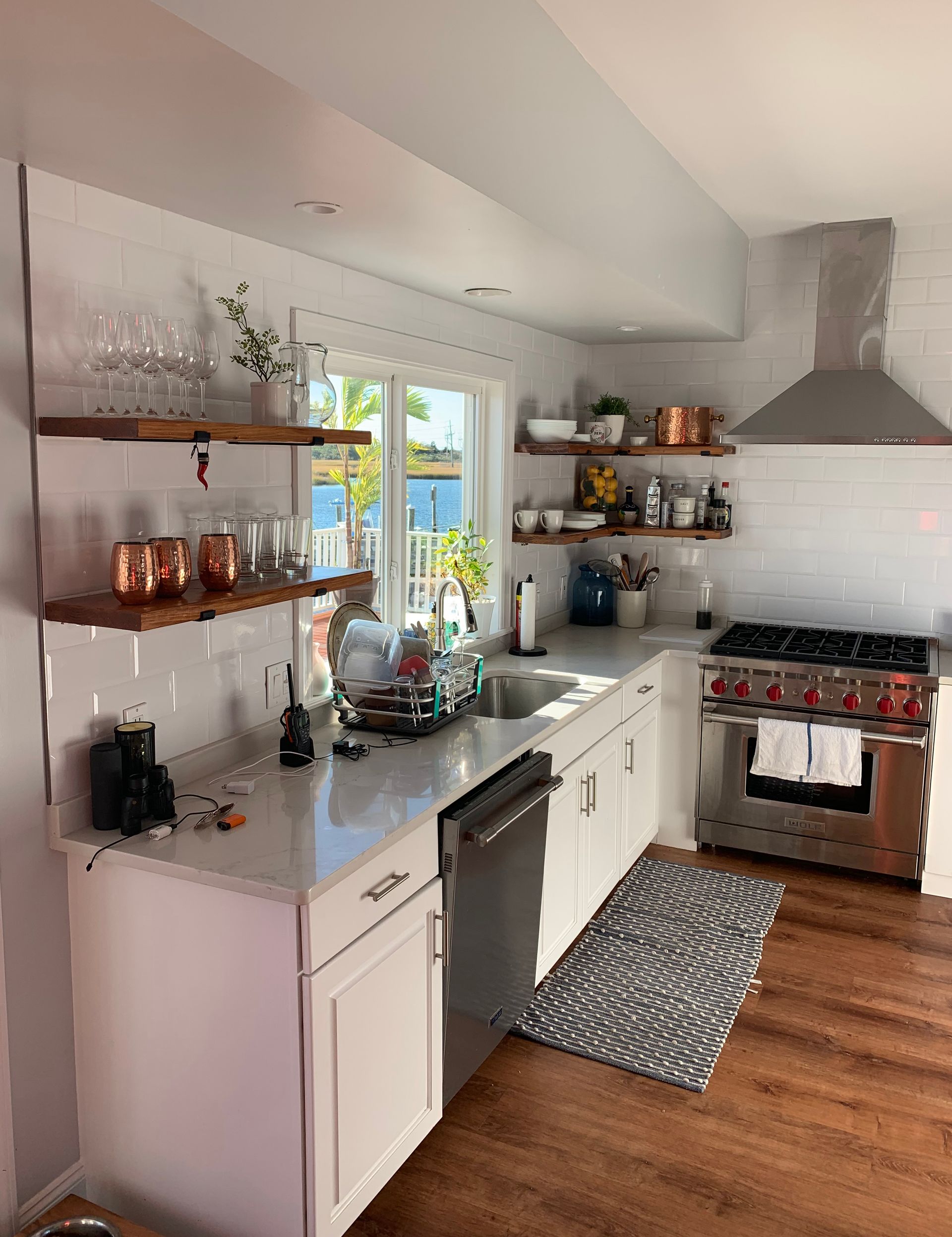 White kitchen with open shelves, a stainless steel range, and a window.
