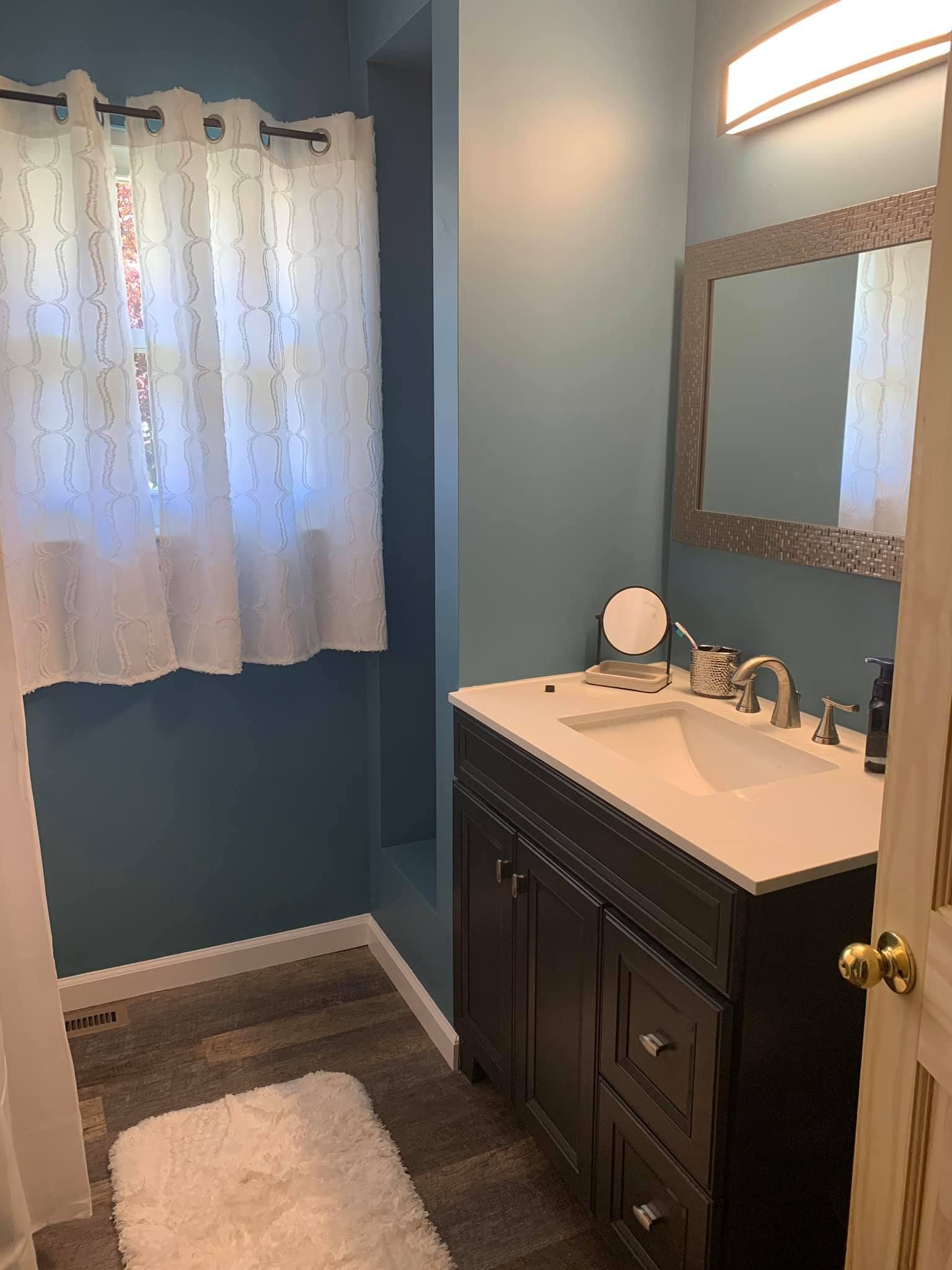 A bathroom with a sink , mirror , and window.