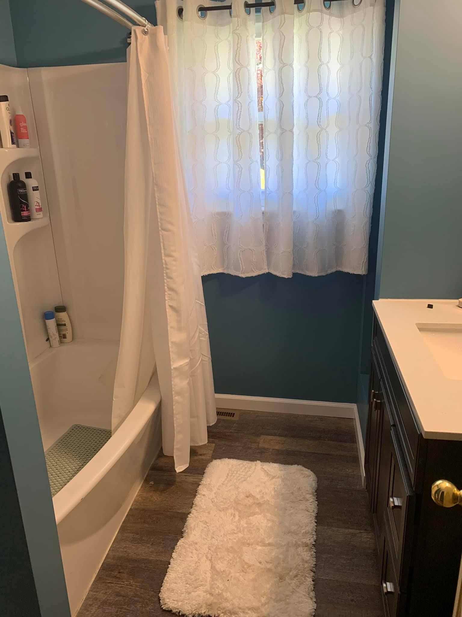 A bathroom with a bathtub , sink , and window.