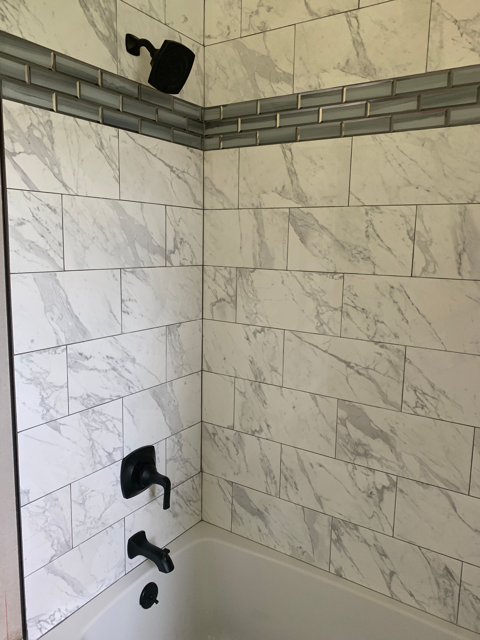 White marble tiled shower with black fixtures.