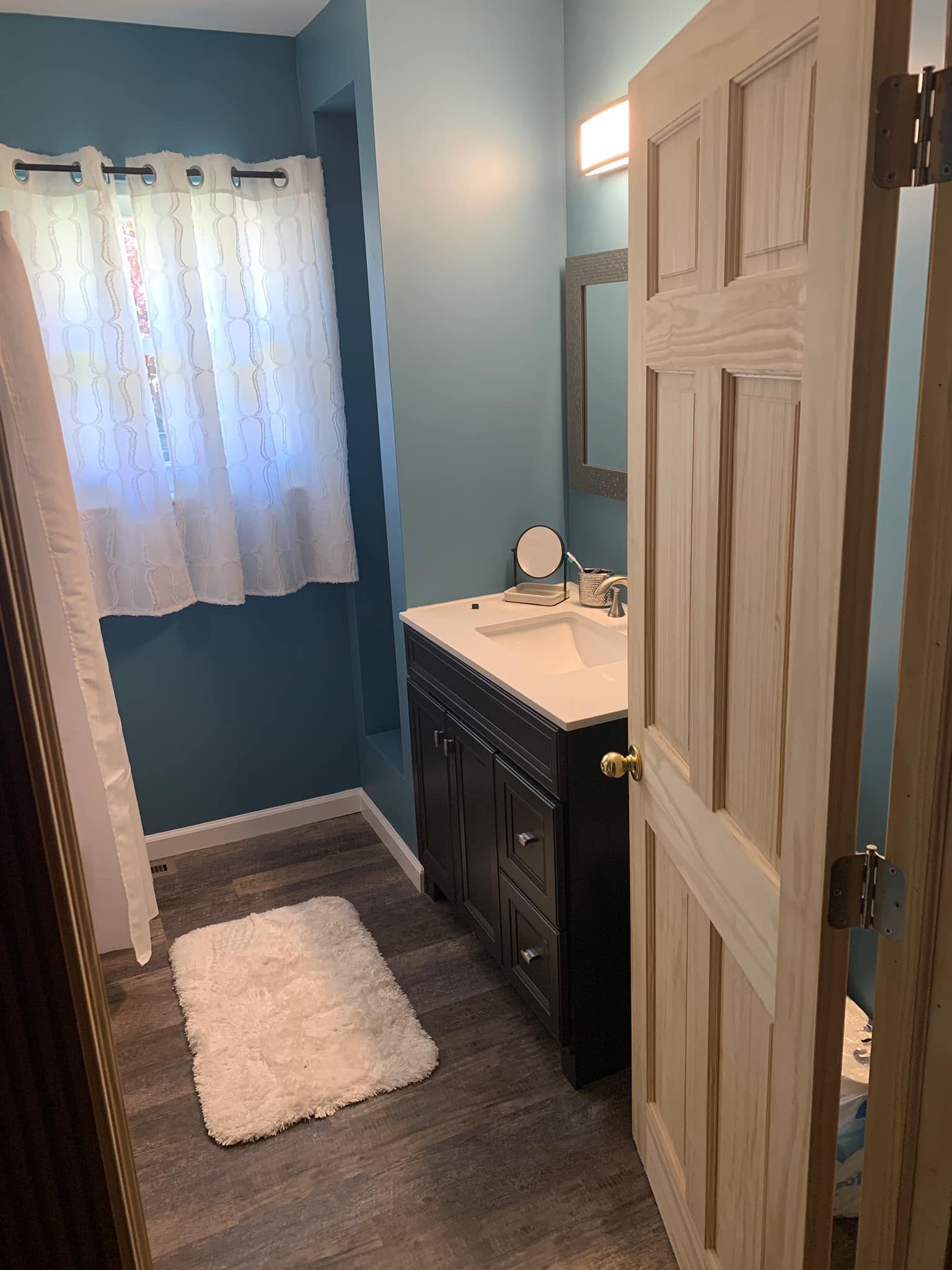 A bathroom with a sink , mirror , and rug.