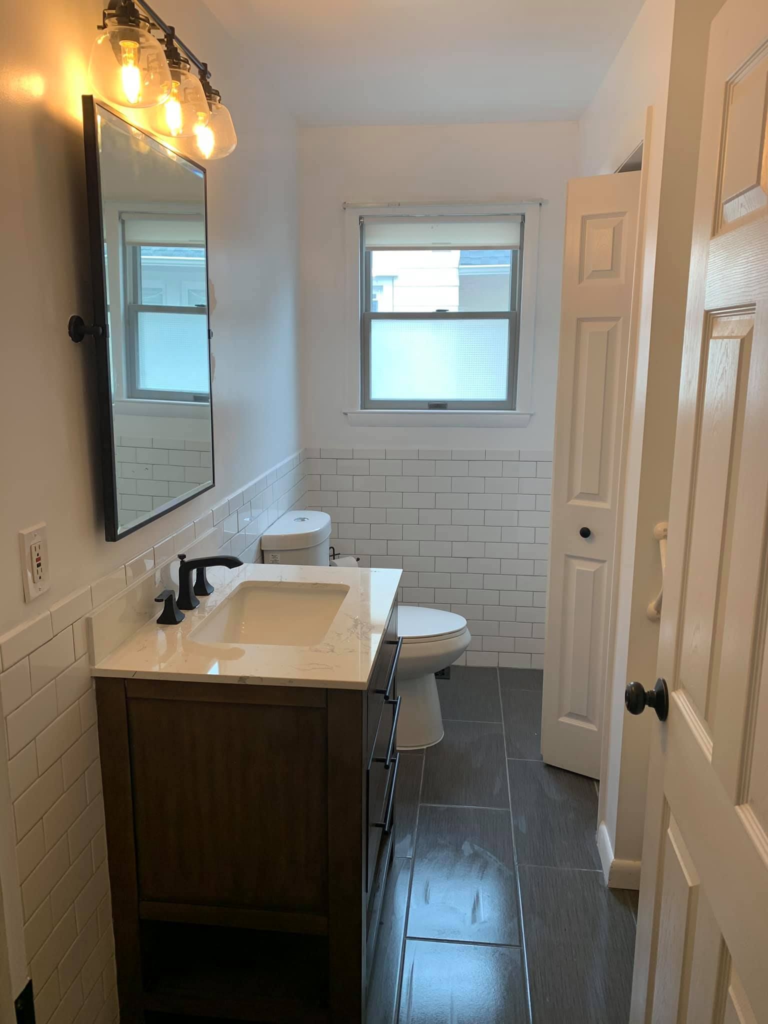 A bathroom with a sink , toilet , mirror and window