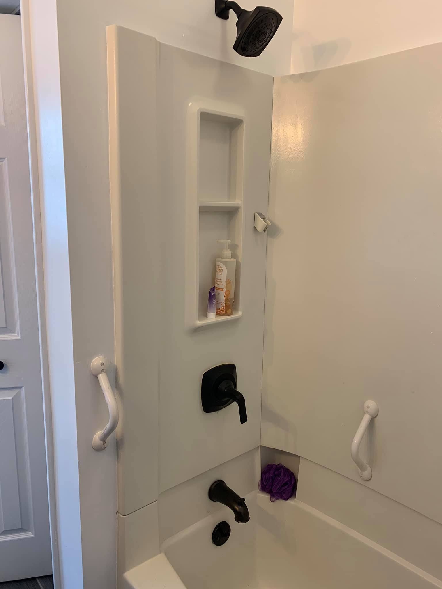 A bathroom with a tub , shower , and shelf.