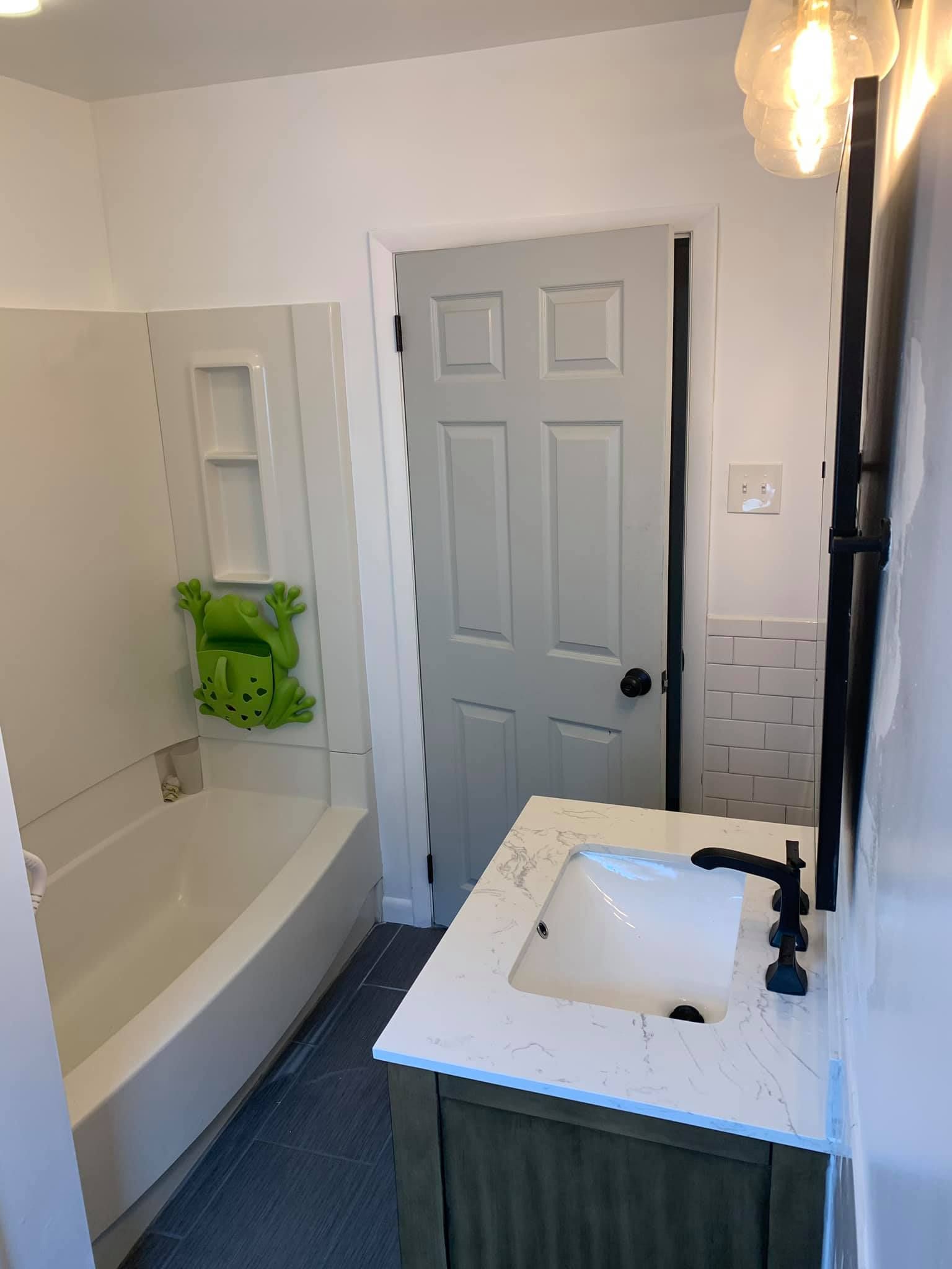 A bathroom with a sink , tub and mirror.