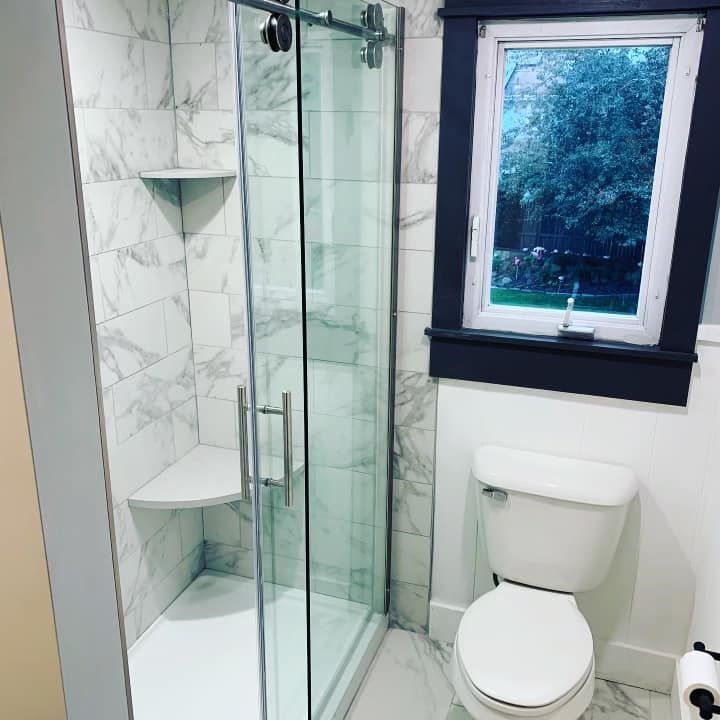 A bathroom with a toilet , shower and window