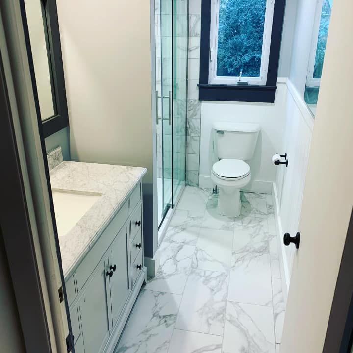 A bathroom with a toilet , sink and shower.