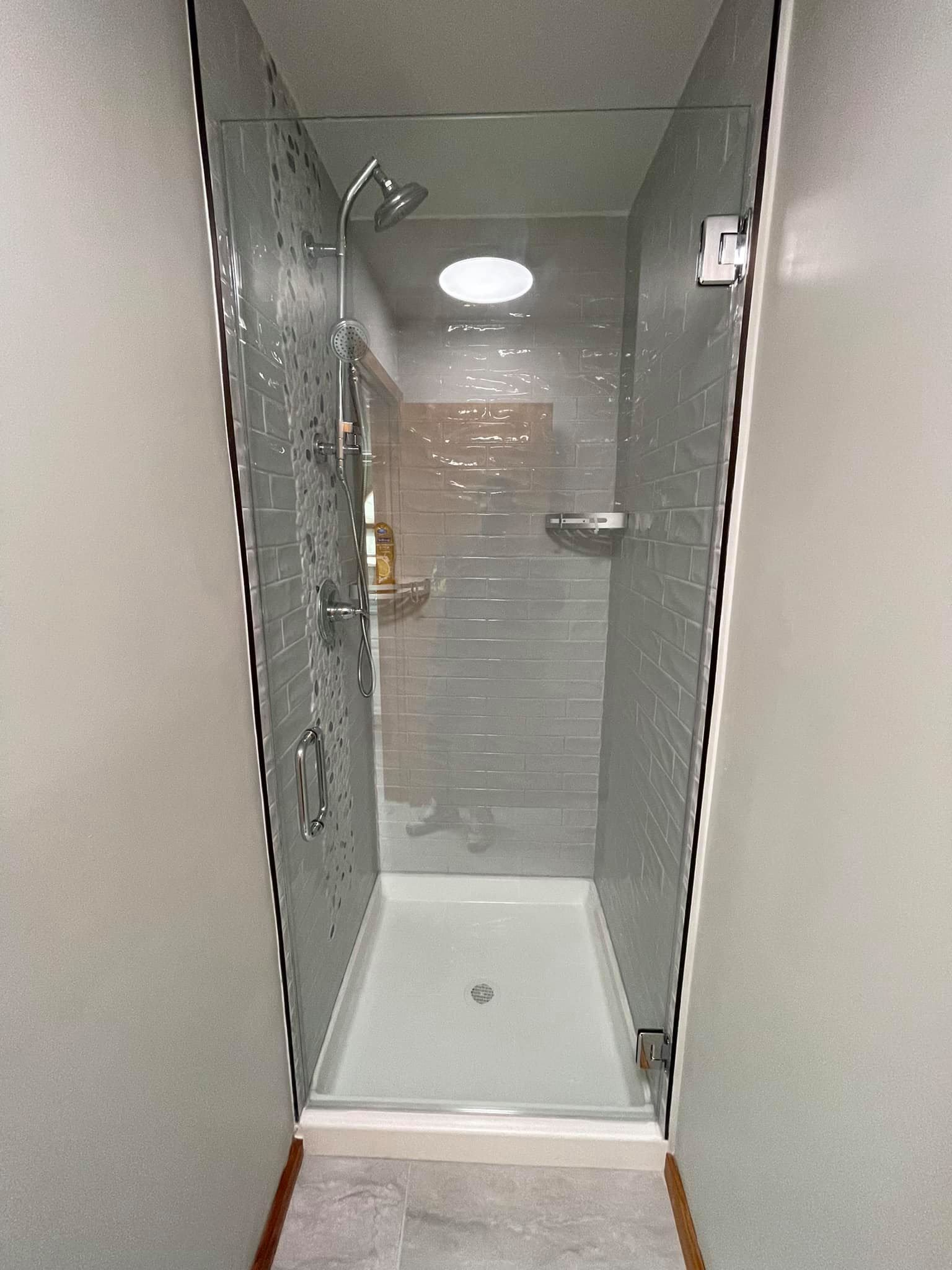 A bathroom with a walk in shower with a glass door.
