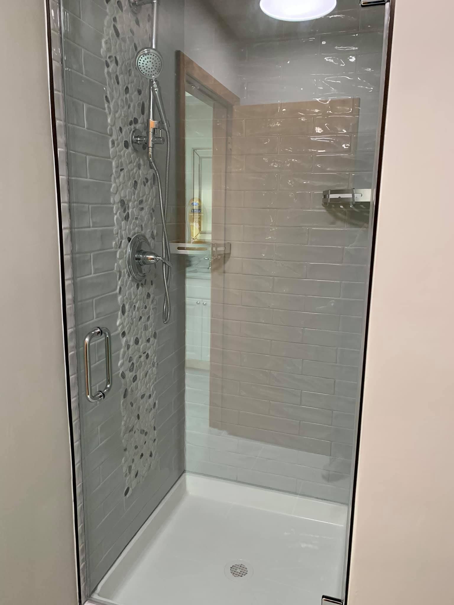A bathroom with a walk in shower with a glass door.