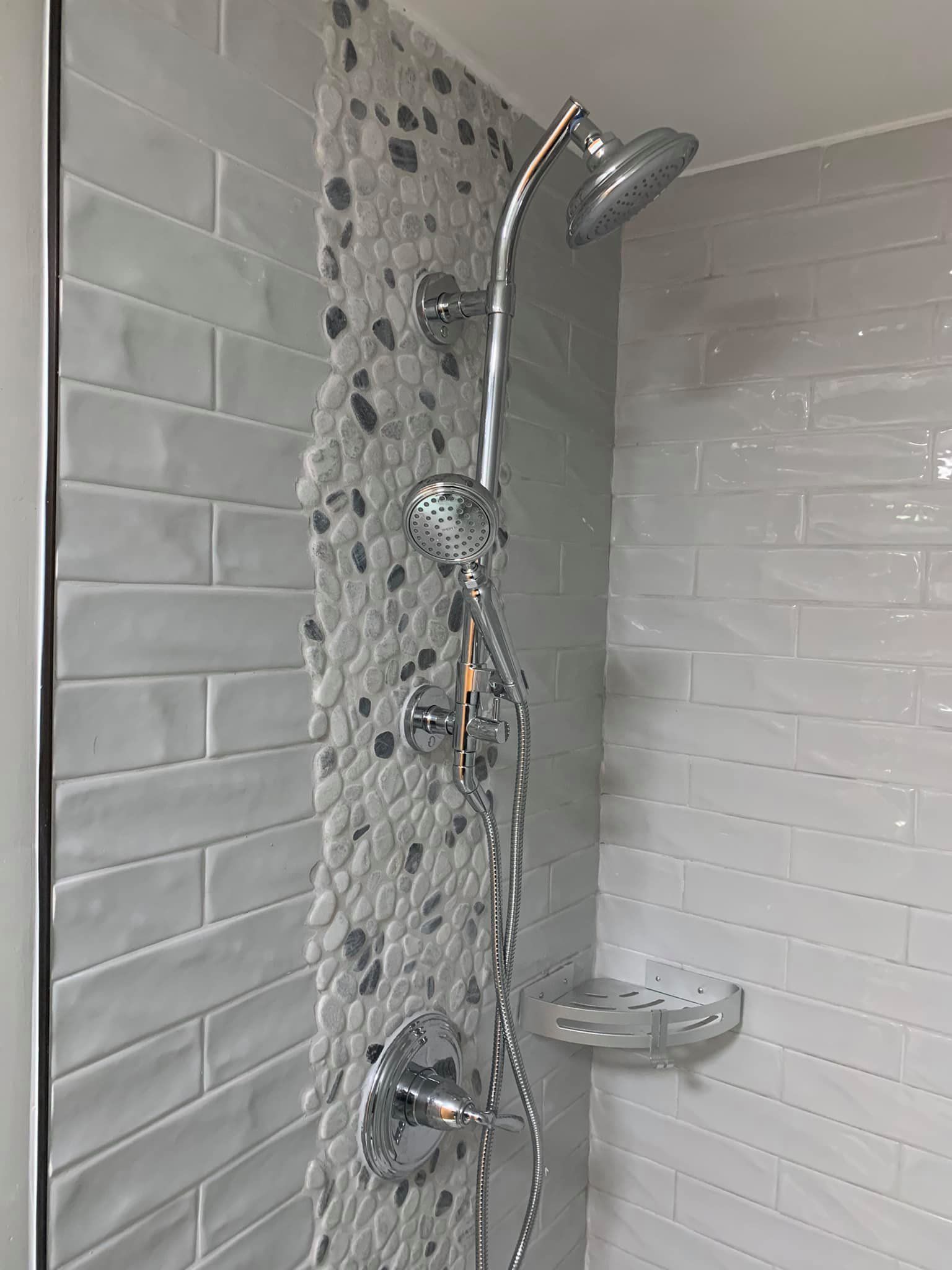 A shower with white tiles and a shower head.