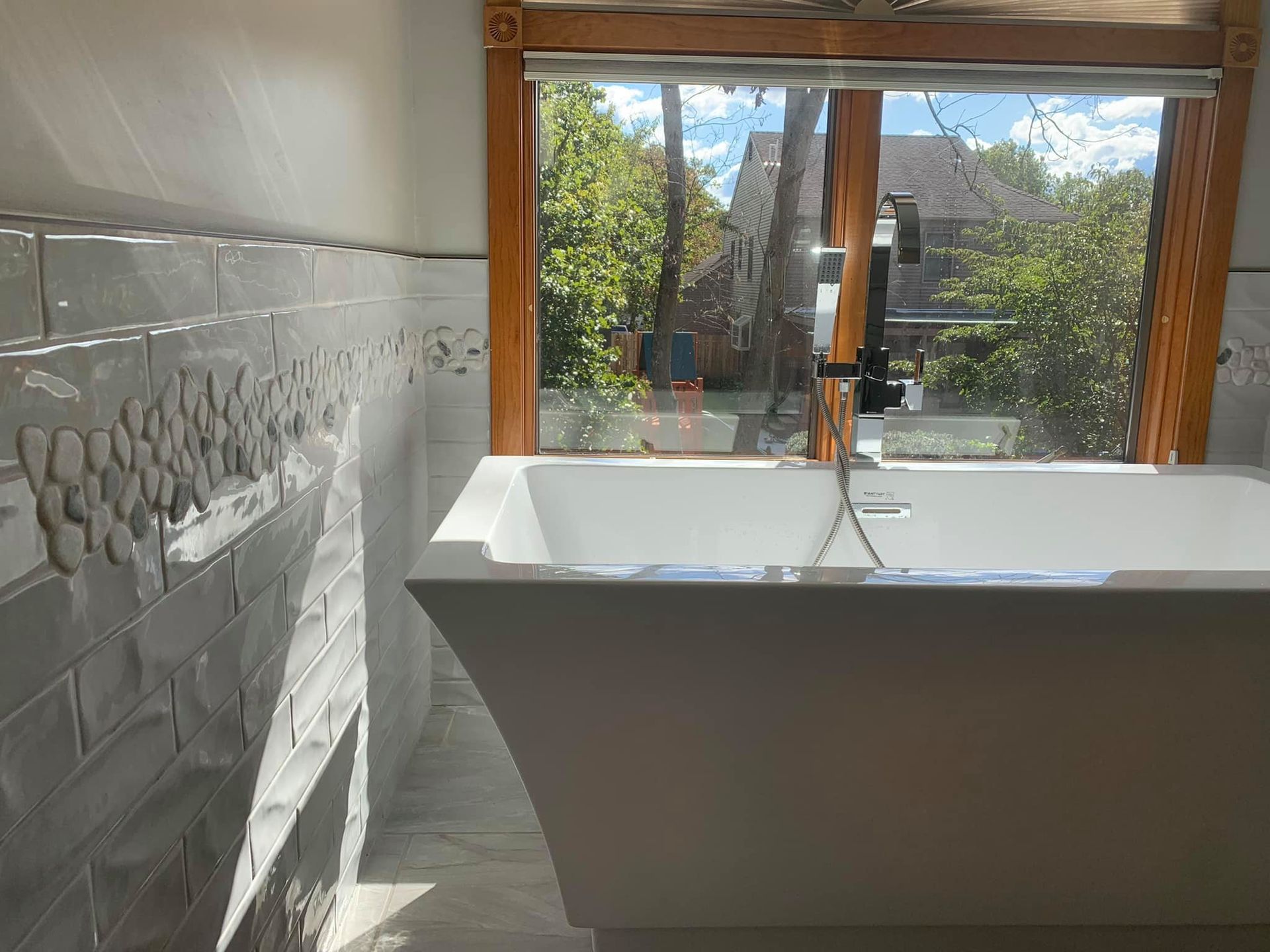 A bathroom with a bathtub and a large window.