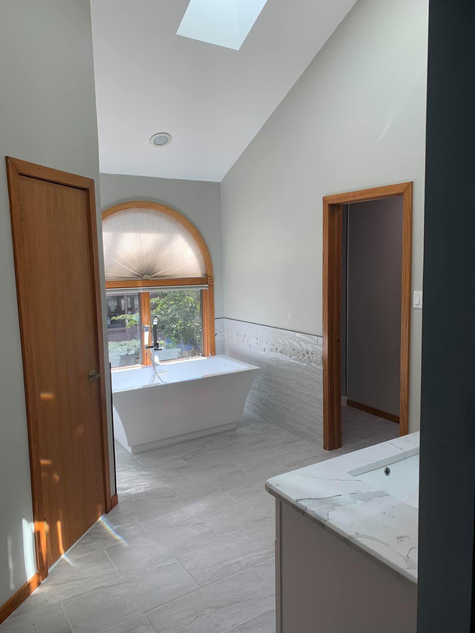 A bathroom with a tub , sink , and window.