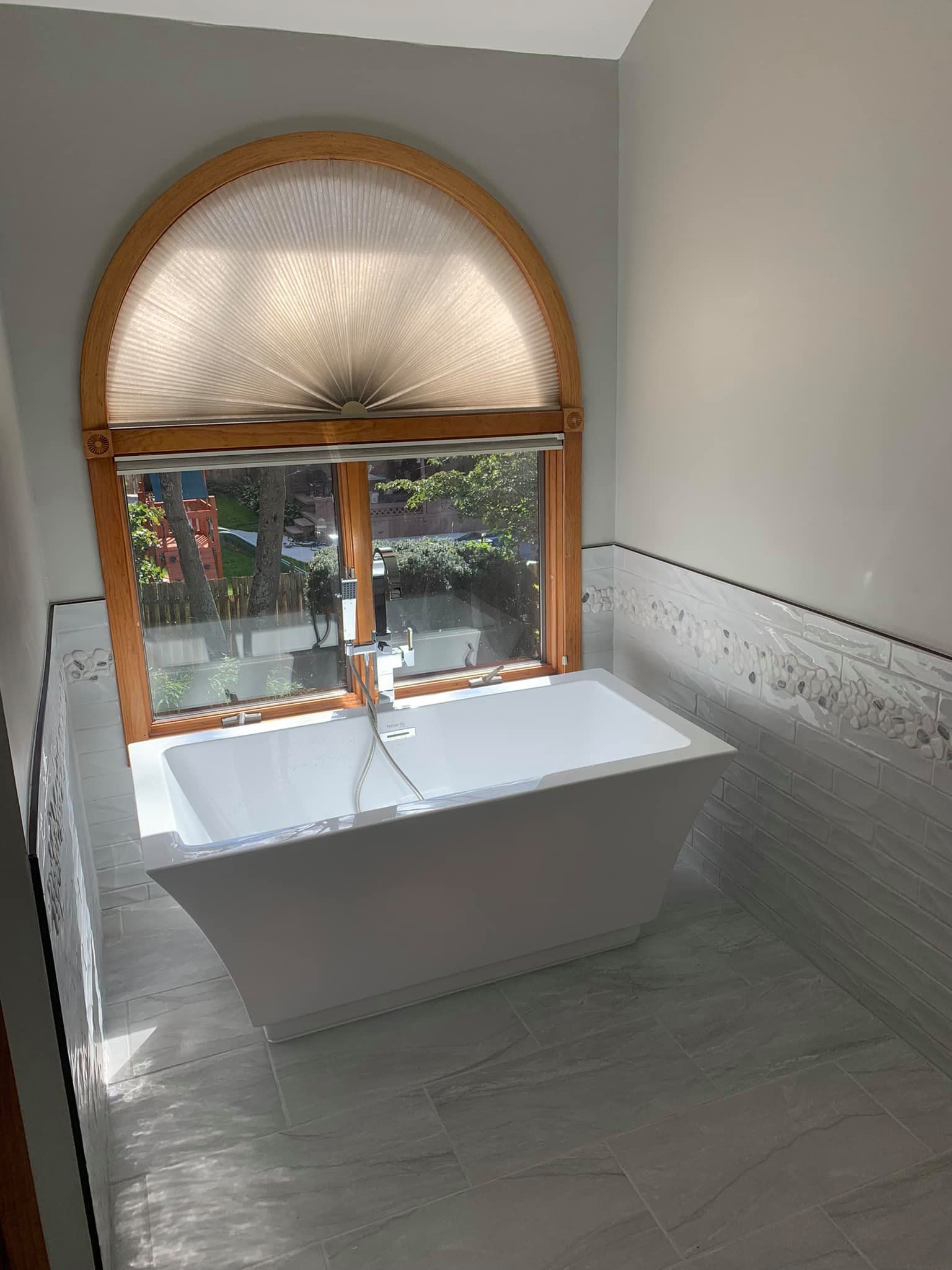A bathroom with a bathtub and a window.