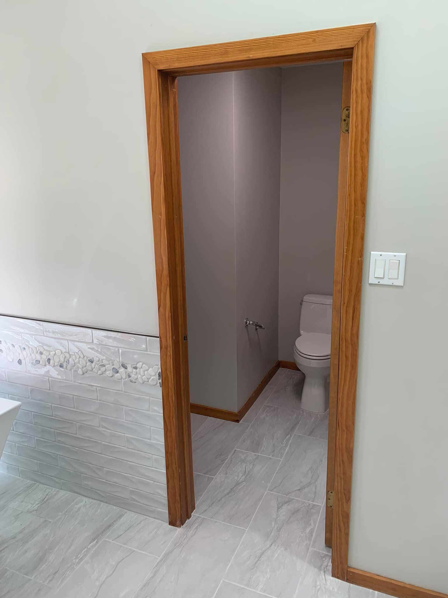 A bathroom with a toilet and a door leading to it.